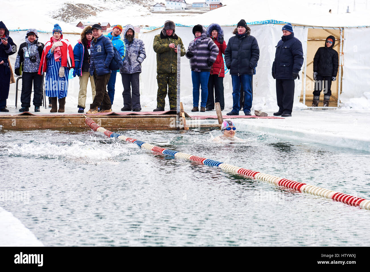 SAHYURTA, Gebiet IRKUTSK, Russland - März 11.2017: Cup des Baikalsees. Winter-Schwimmwettkampf. Schar von Fans am Rand der Eisloch zum Schwimmen krank sind Stockfoto
