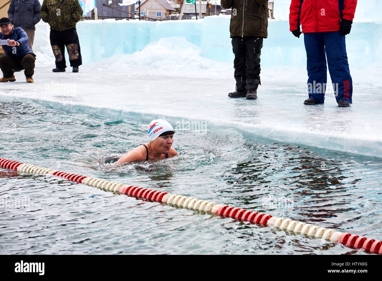 SAHYURTA, Gebiet IRKUTSK, Russland - März 11.2017: Cup des Baikalsees. Winter-Schwimmwettkampf. Schwebende Frau in sehr kaltem Wasser Stockfoto