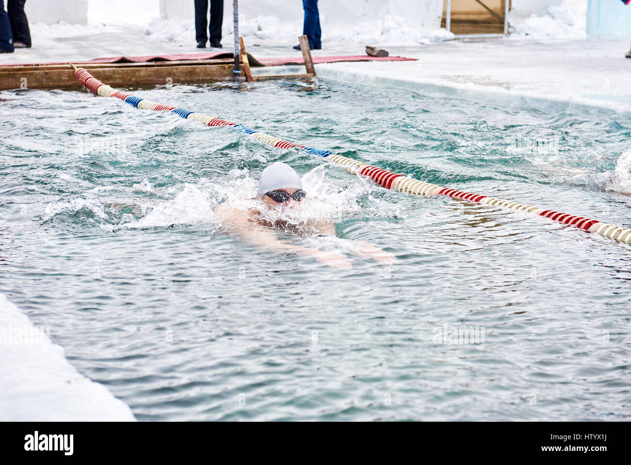 SAHYURTA, Gebiet IRKUTSK, Russland - März 11.2017: Cup des Baikalsees. Winter-Schwimmwettkampf. Ein Mann schwimmt auf Wasserweg mit Brustschwimmen Stockfoto