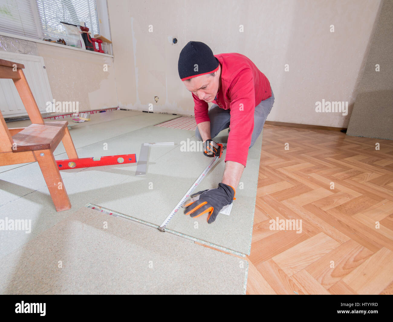 In der Wohnung zu reparieren. Den Bodenbelag im Zimmer legt der Mann. Stockfoto
