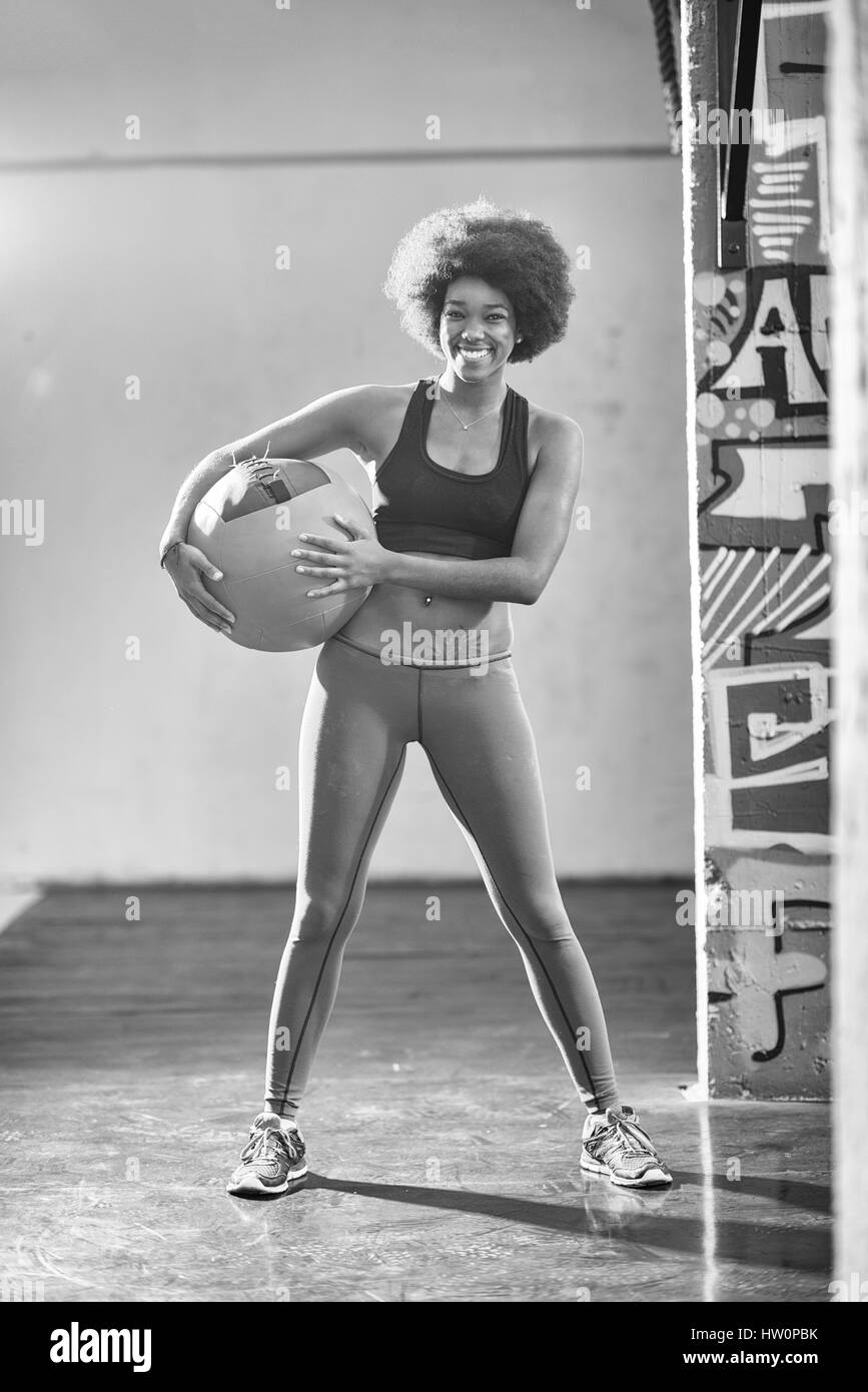 Porträt einer jungen schönen afroamerikanische Frau mit Crossfit Ball im Fitness-Studio Stockfoto