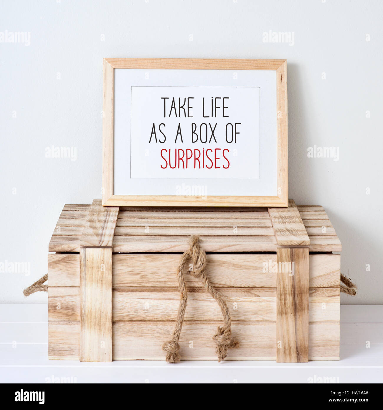 ein Holz-gerahmte Bild mit dem Text nehmen Leben wie eine Schachtel mit Überraschungen, geschrieben auf einer rustikalen Holzkiste gelegt Stockfoto