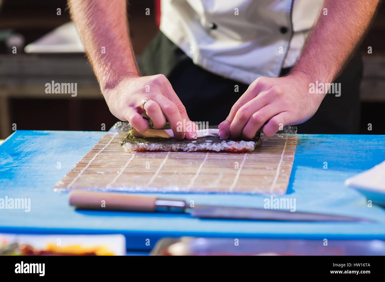 Männliche Hände berühren Bambusmatte. Kleine Matte auf dem Board zu kochen. Japanische Koch bei der Arbeit. Mann bereitet Sushi-Rollen. Stockfoto