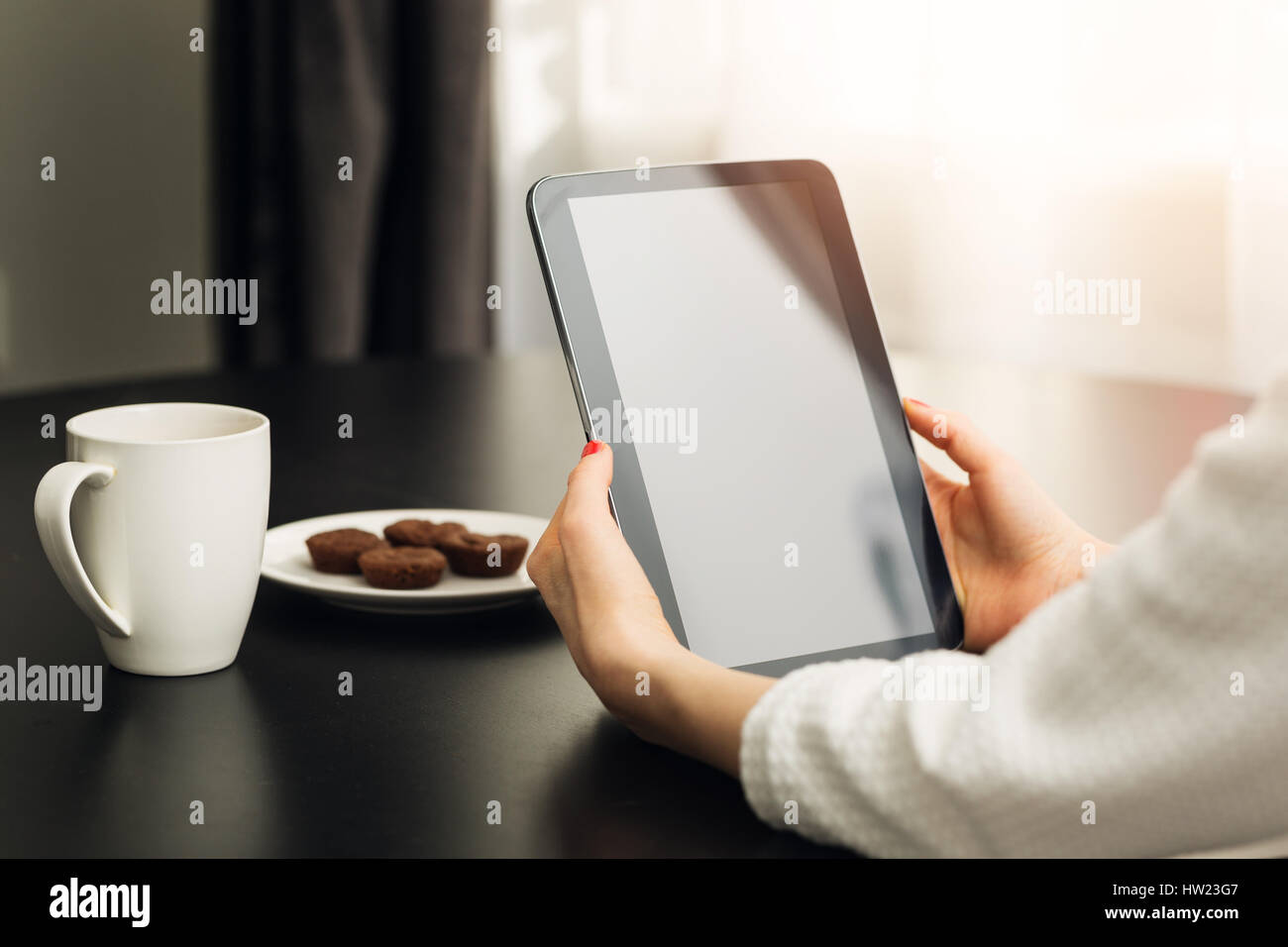 Frau sitzt durch die Tabelle zu Hause und mit digitalen e-Book-Reader Stockfoto