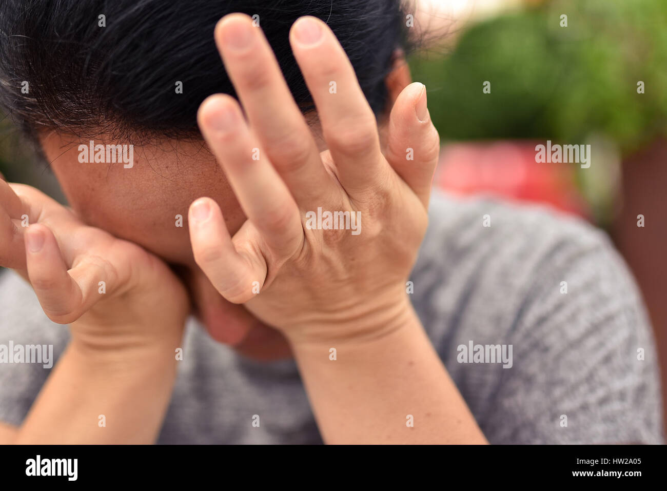 Junge attraktive Frau verbirgt ihr Gesicht in den Handflächen lässig gekleidet. Stockfoto