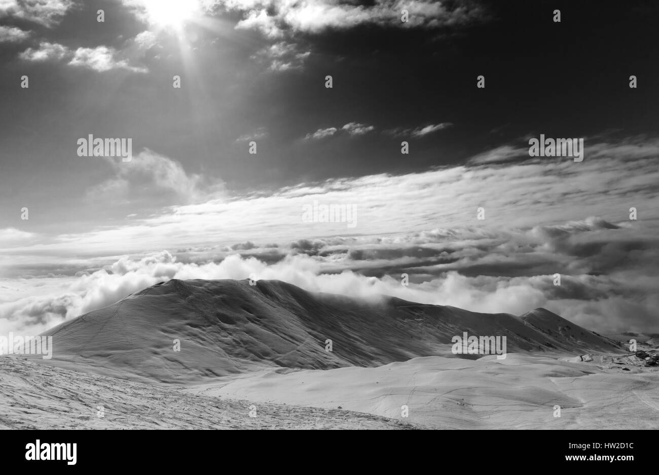 Schwarzweißansicht auf Off-Piste Hang in Wolken und Himmel mit Sonne. Kaukasus, Georgien, Region Gudauri. Stockfoto