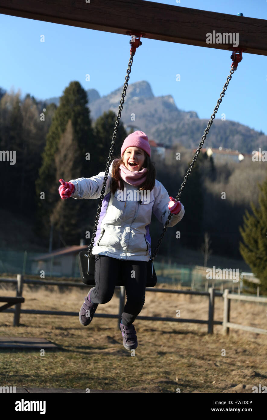 hübsches kleines Mädchen spielt auf einem Spielplatz in den Bergen im winter Stockfoto