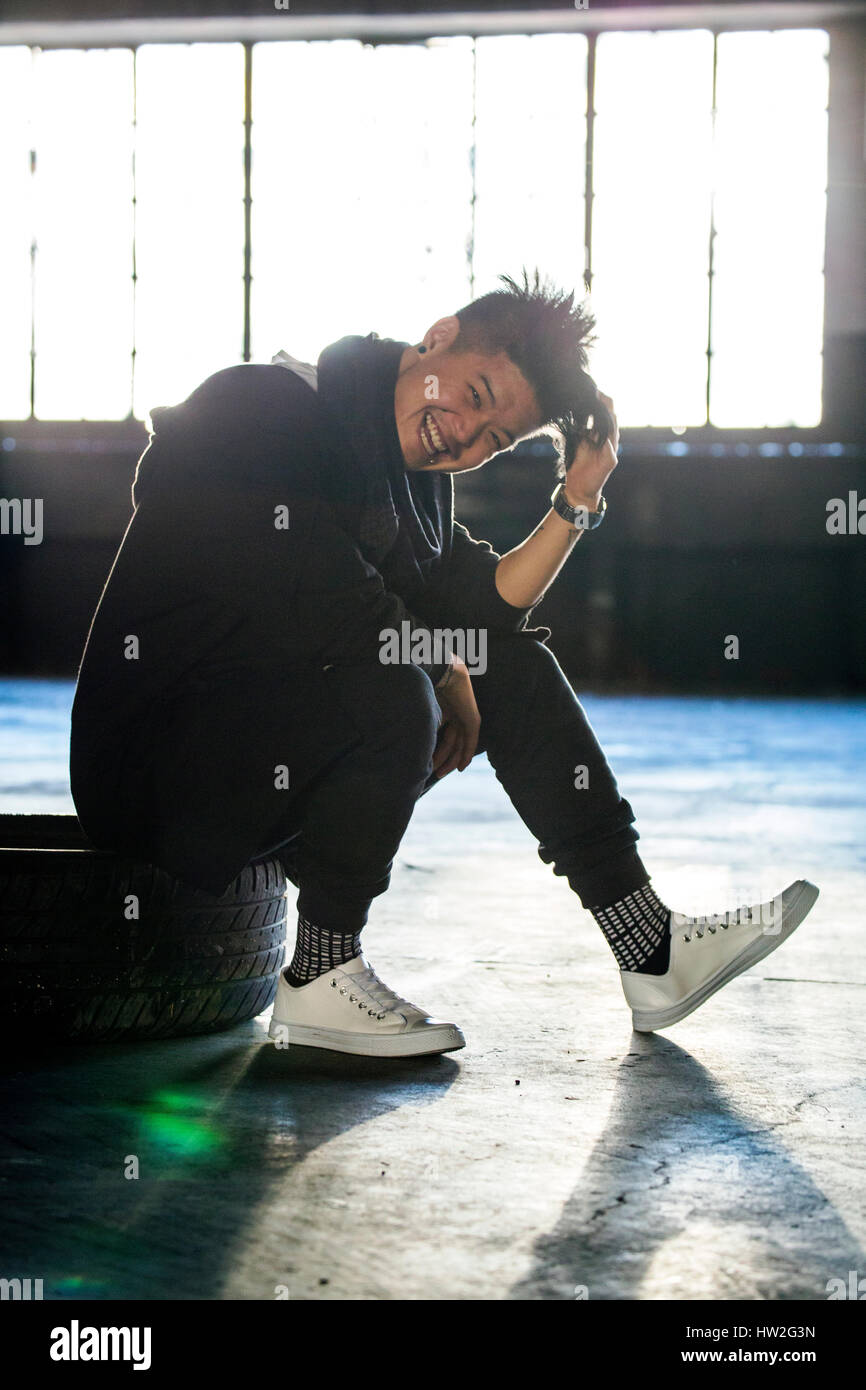 Lachend androgynen asiatischen Mann sitzt auf Rad Stockfoto