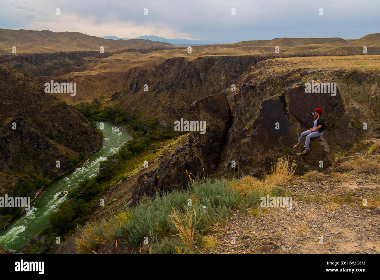 Kaukasische Frau sitzen auf Bergfelsen fotografieren Fluss Stockfoto