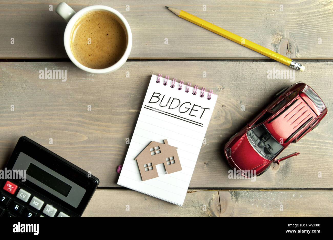 Budget handschriftlich in einem Notizbuch mit einem Miniatur-Auto und Haus Stockfoto