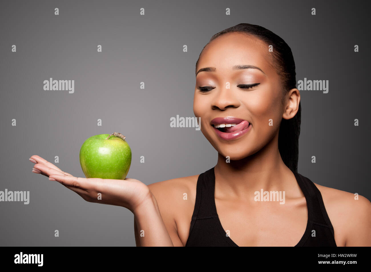 Schöne gesunde glücklich lecken schwarze Asiatin mit köstlichen Apfel in der Hand. Stockfoto