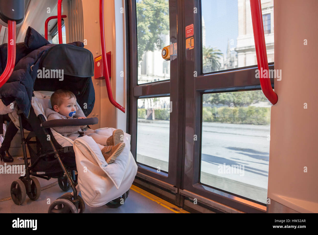 Baby junge Spaß während der Fahrt bei Straßenbahn, Spanien. Er sitzt auf seinem buggy Stockfoto