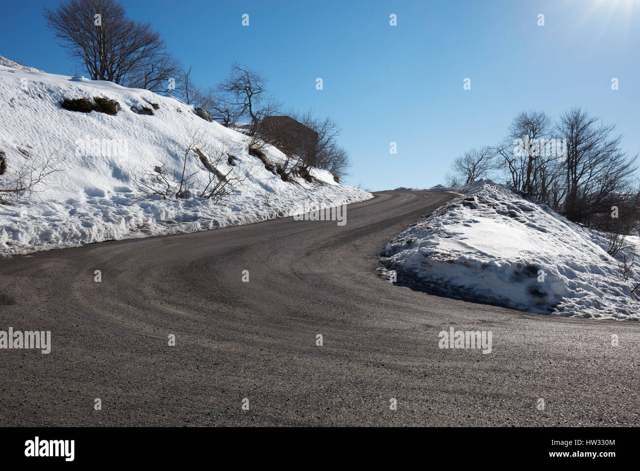 Leer, große Bergstraße mit Schnee auf Seiten, klaren, blauen Himmel in einem sonnigen winter Stockfoto