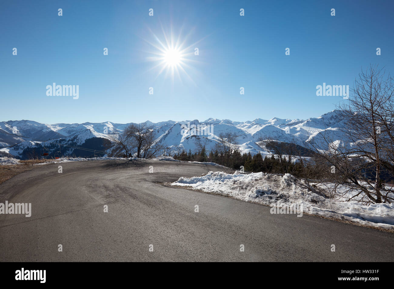 Leere Bergstraße auf Alpen mit Kurve in einem sonnigen Wintertag Stockfoto