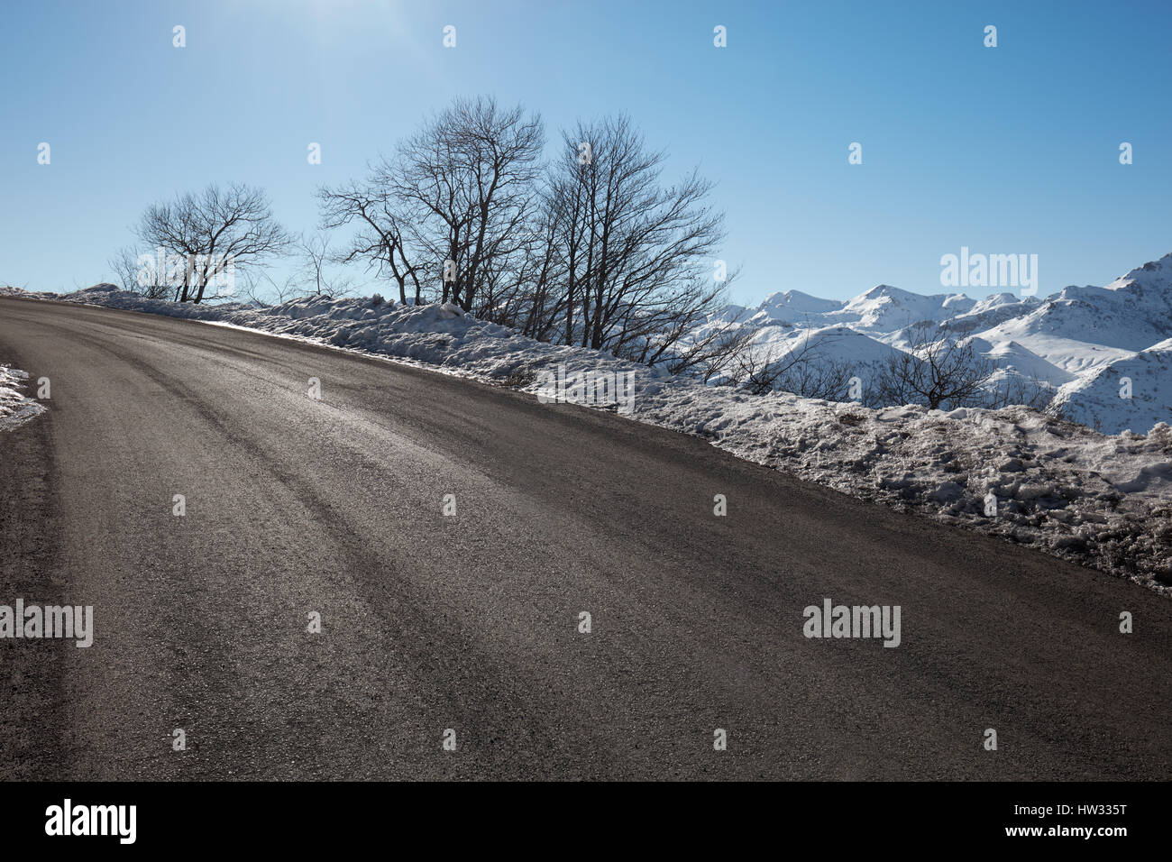 Leere alpine Bergstraße im Winter, blauer Himmel an einem sonnigen Tag Stockfoto