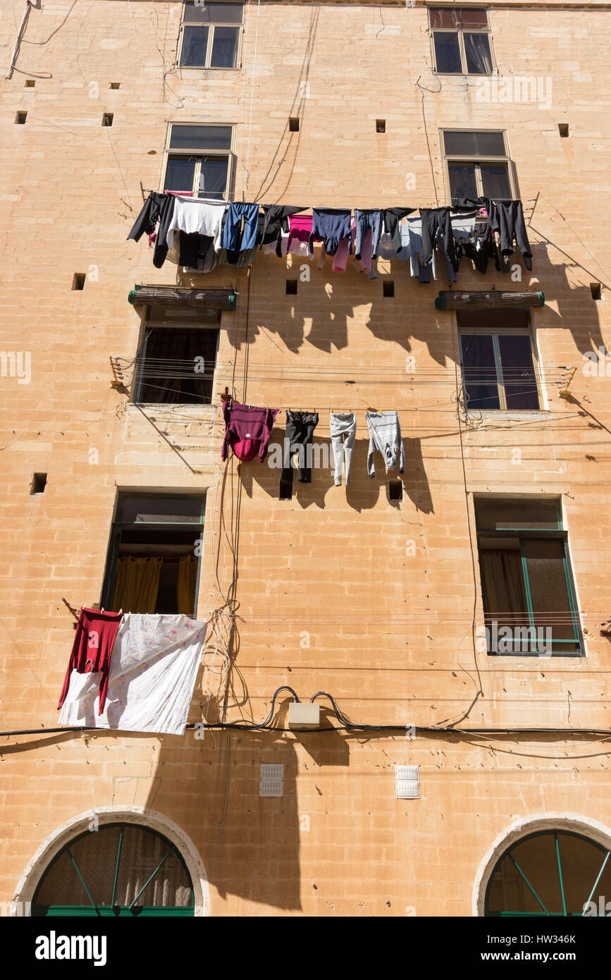 Reinigung und Wäsche hängen zum Trocknen auf Wäscheleinen auf ein altes Gebäude in Valletta Malta Stockfoto