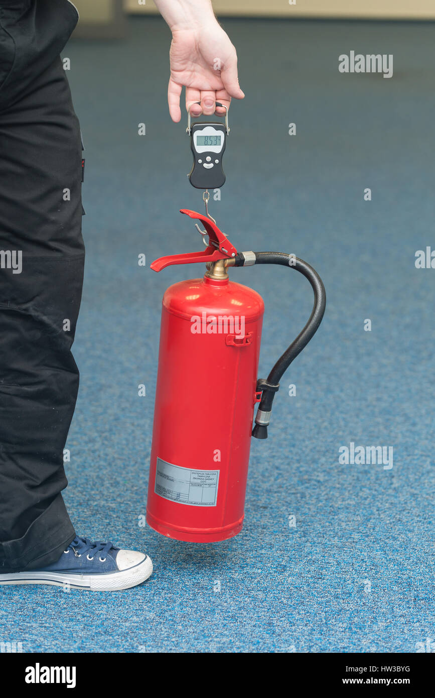 mit einem Gewicht von einen Feuerlöscher, eine Überprüfung der Feuer kämpfende Ausrüstung Stockfoto