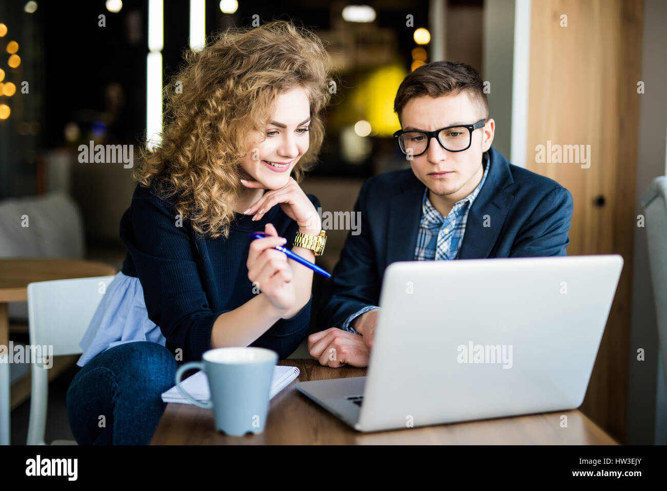 Gruppe von zwei Kollegen arbeiten über Laptop zu diskutieren, in einem modernen Büro im Hintergrund Stockfoto