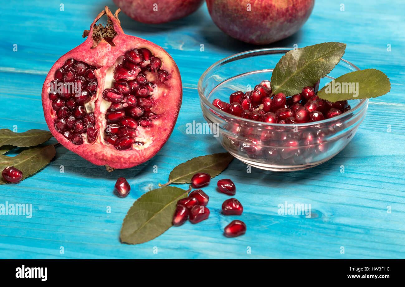 Reife Granatapfel-Frucht mit Saft auf blauer Farbe Holz Vintage-Hintergrund. Selektiven Fokus. Stockfoto