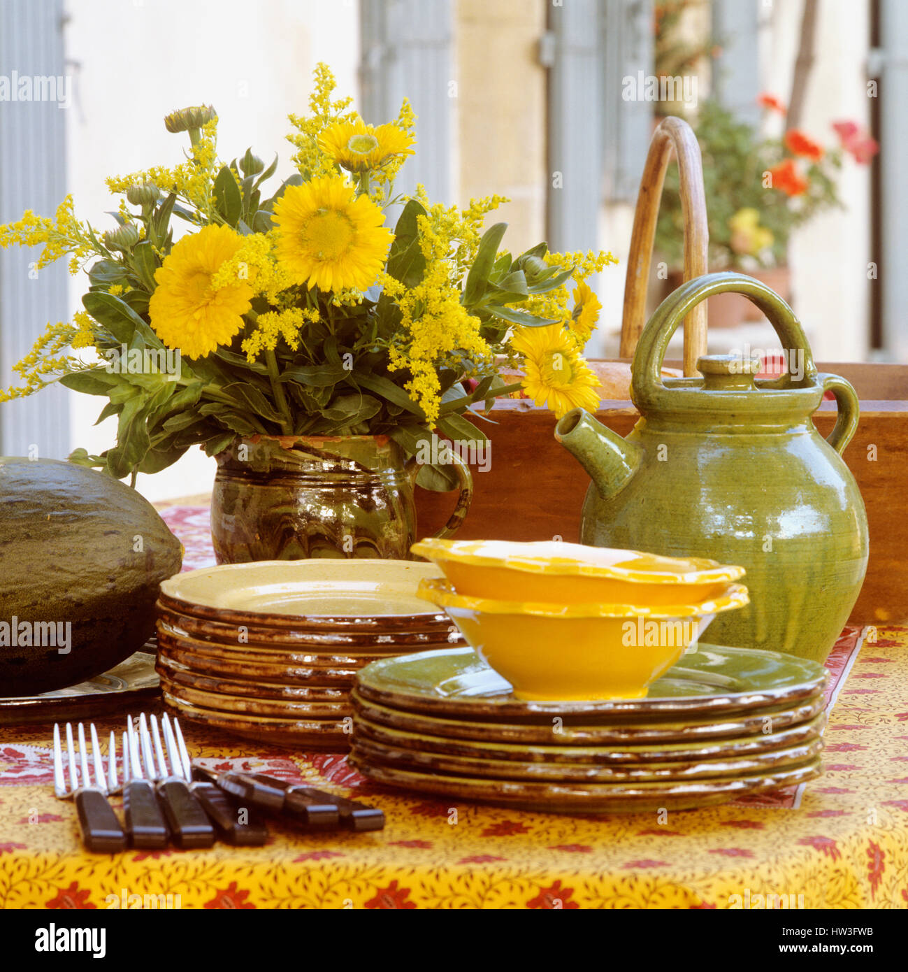Geschirr und Besteck neben Vase mit Blumen. Stockfoto