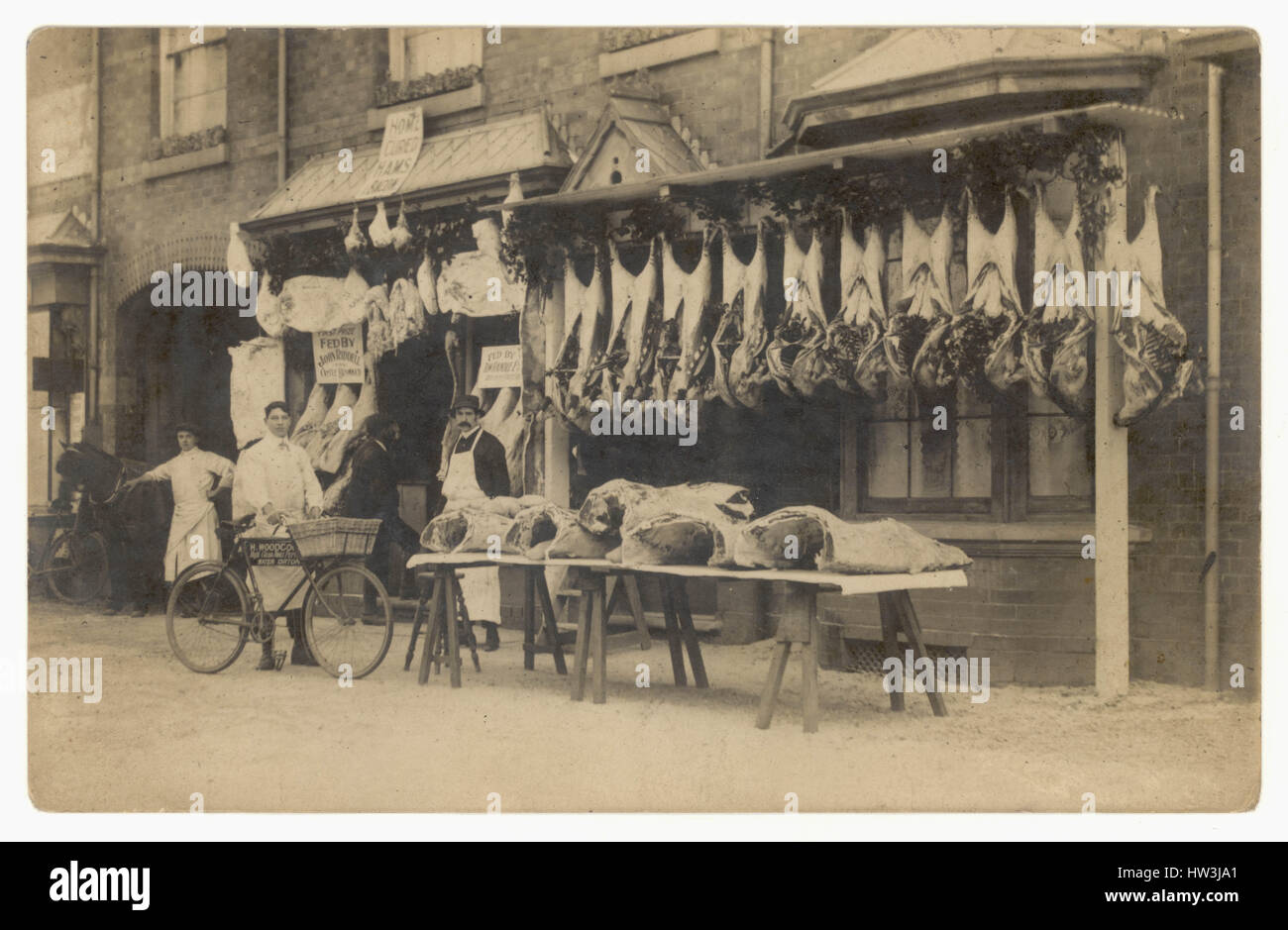 Postkarte der ursprünglichen Edwardianischen Ära, in der Fleisch- und Rindfleisch draußen hängen, mit Männern - Personal / Assistent / Assistenten und Lieferfahrrad, Erdington, Birmingham, England, Großbritannien um 1905 Stockfoto