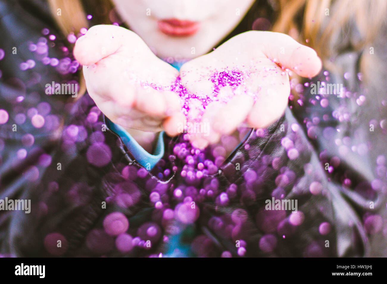 Rothaarige Kind bläst glitzernden lila Konfetti Stockfoto
