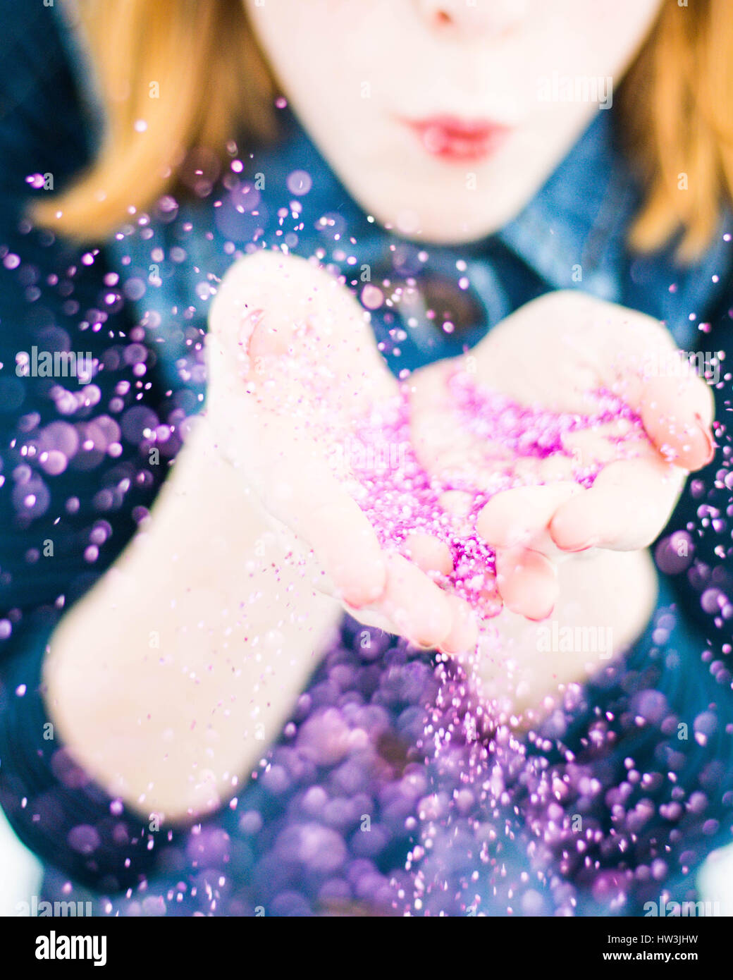 Rothaarige Kind bläst glitzernden lila Konfetti Stockfoto