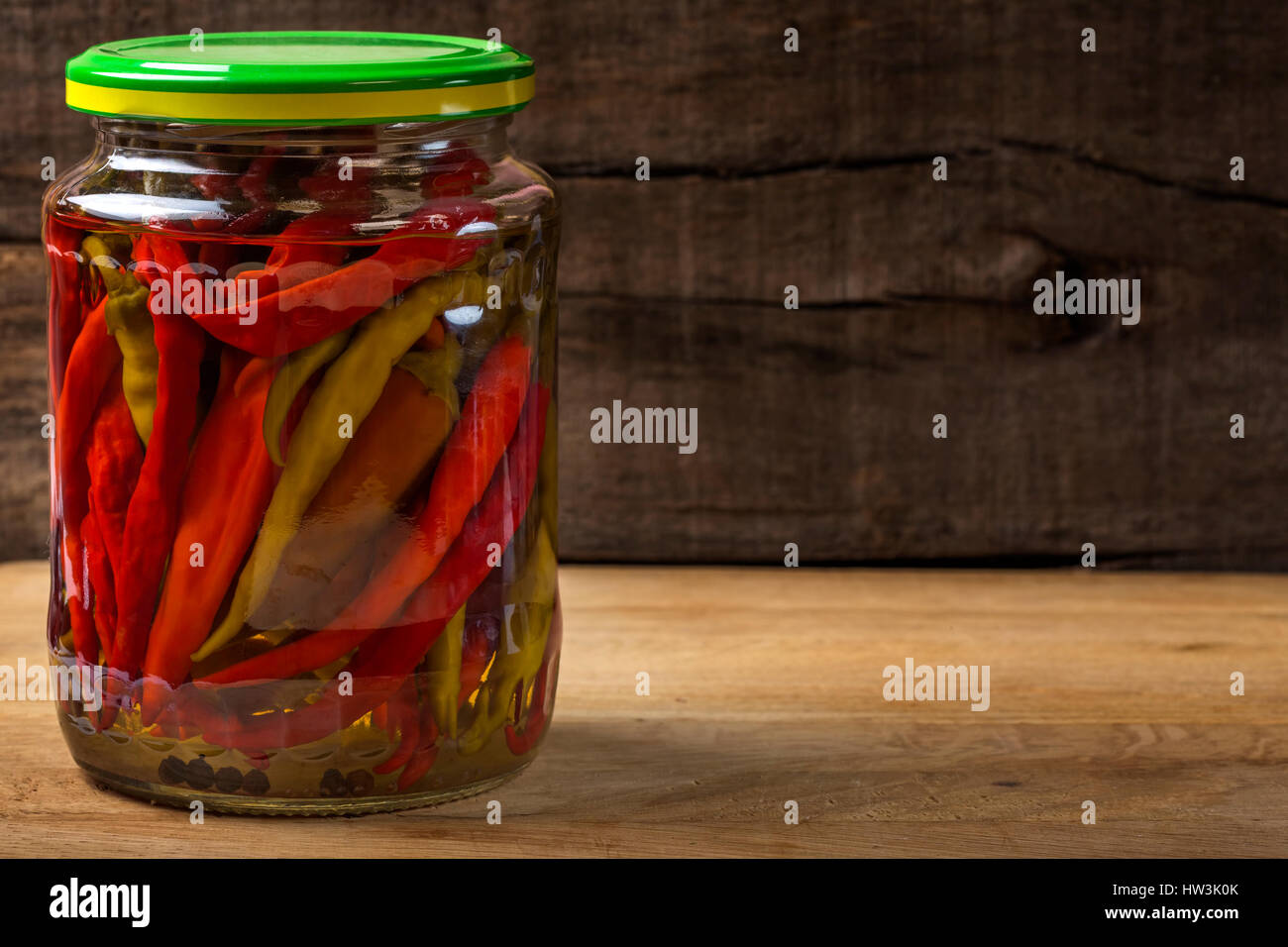 Marinierte Peperoni in Glas über hölzerne Hintergrund Stockfoto