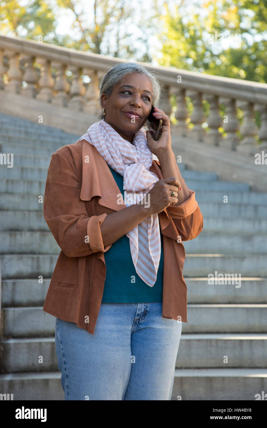 Schwarze Frau auf Steintreppe reden über Handy Stockfoto
