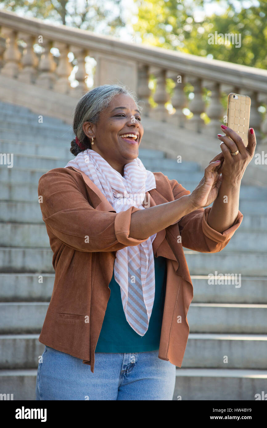 Schwarze Frau posiert für Handy Selfie auf Steintreppe Stockfoto