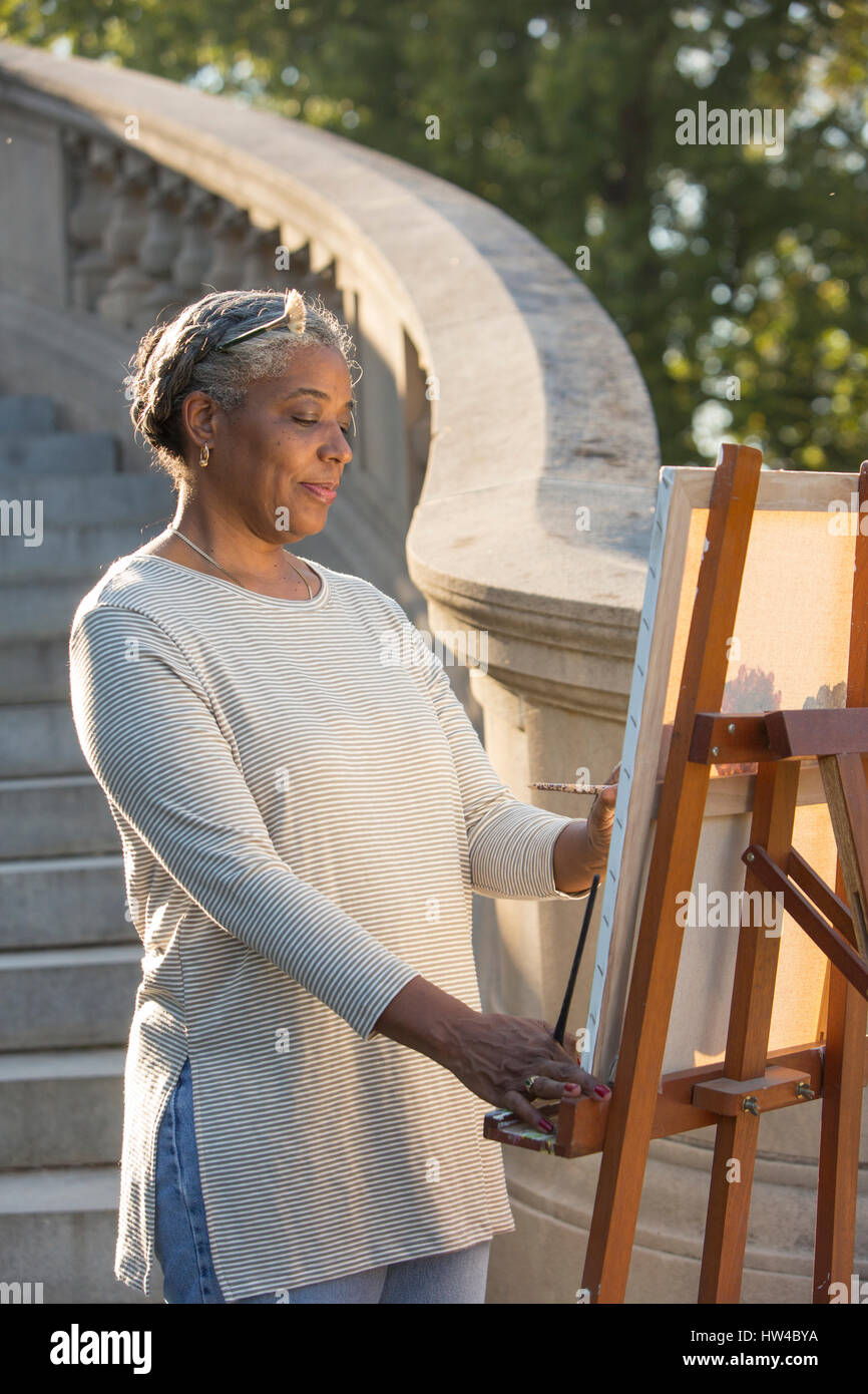 Schwarze Frau malen auf Leinwand in der Nähe von Steintreppe Stockfoto