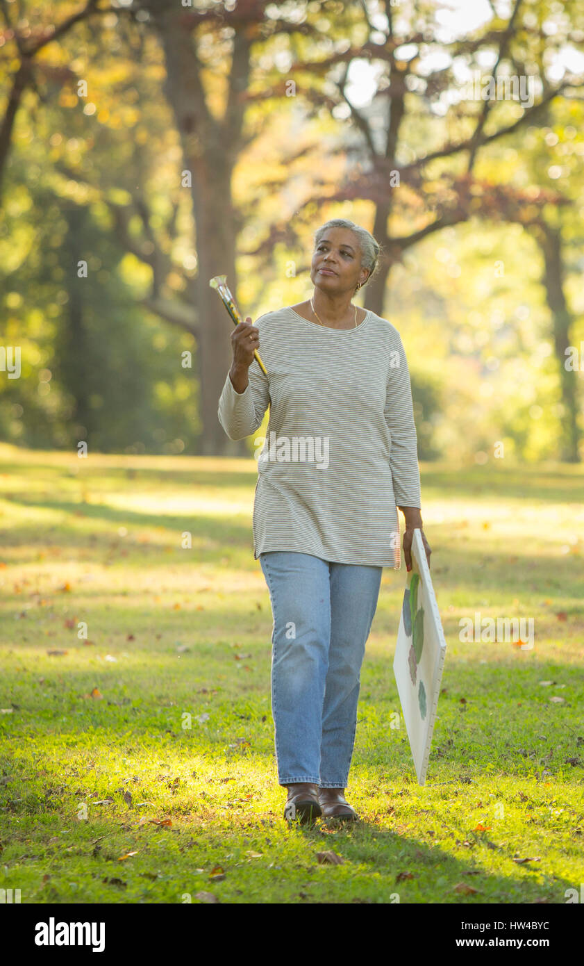 Nachdenklich schwarze Frau mit Pinsel und Leinwand im park Stockfoto