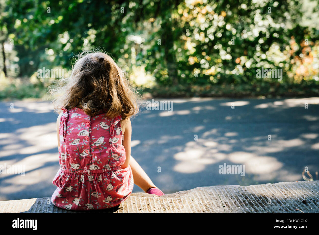 Kaukasische Mädchen sitzen am Straßenrand Stockfoto