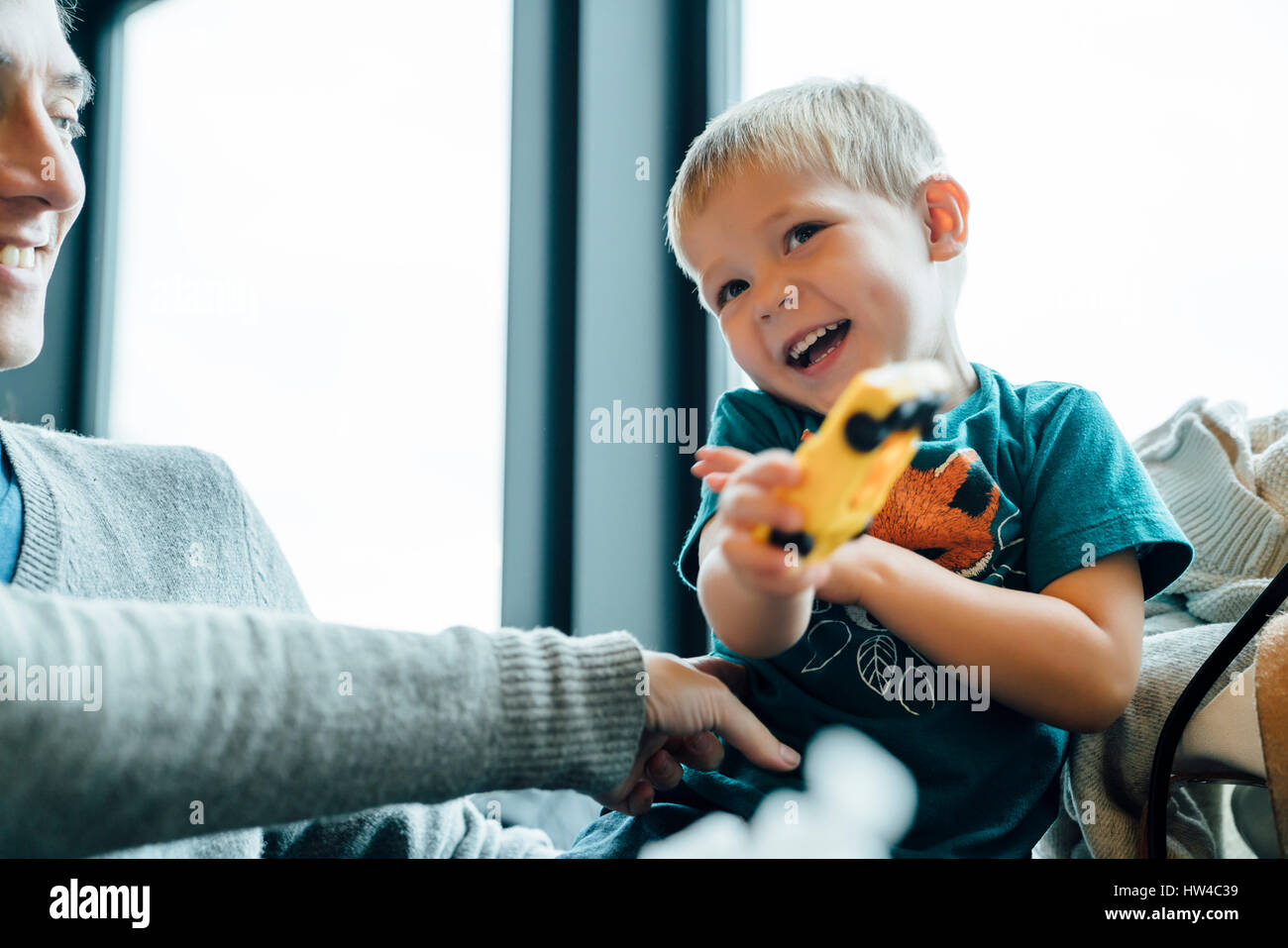 Arm der Mutter kitzeln Sohn halten Spielzeugauto Stockfoto