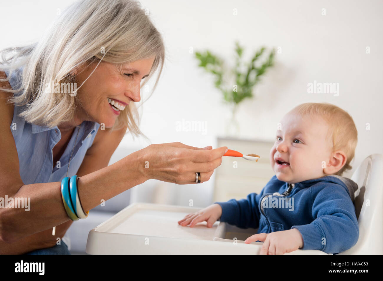 Lächelnd kaukasischen Großmutter Fütterung Baby Enkel im Hochstuhl Stockfoto