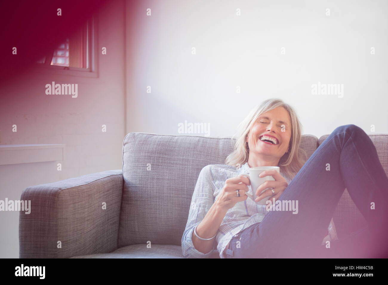 Lachende Frau kaukasischen auf Sofa Kaffee trinken Stockfoto