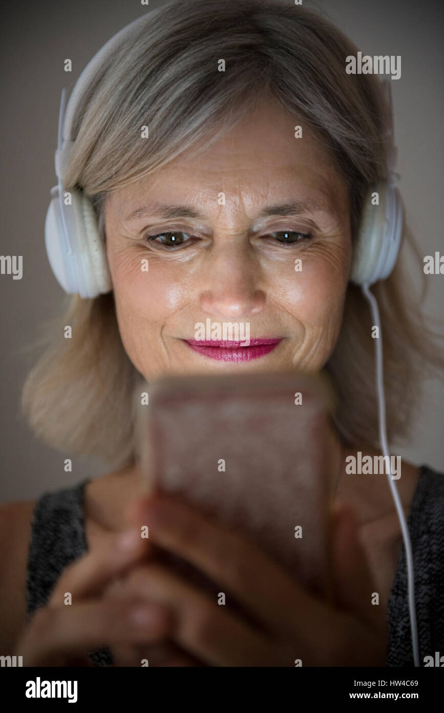 Lächelnde Frau kaukasischen anhören von Musik auf Handy Stockfoto