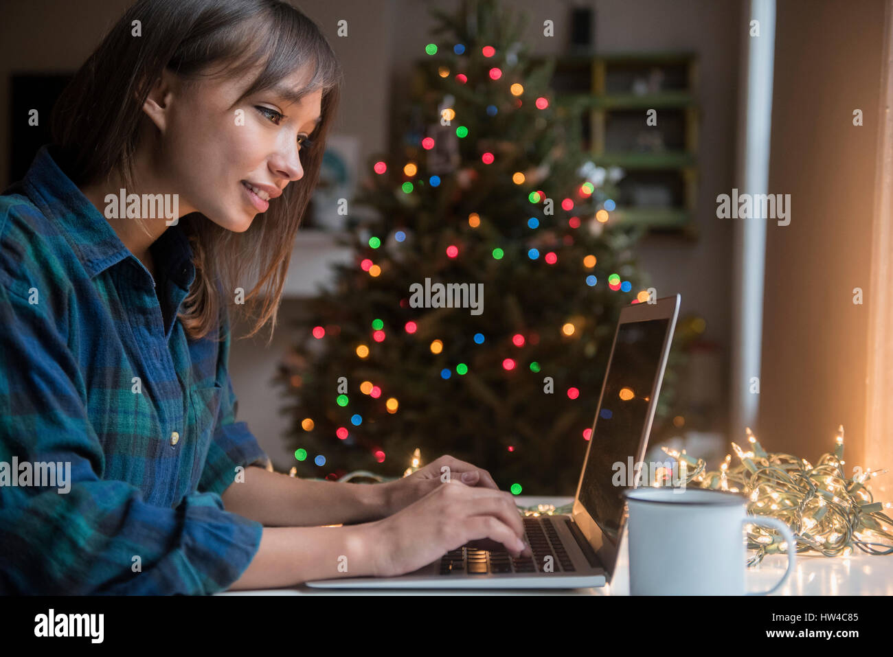 Gemischte Rennen Frau mit Laptop in der Nähe von Christmas tree Stockfoto
