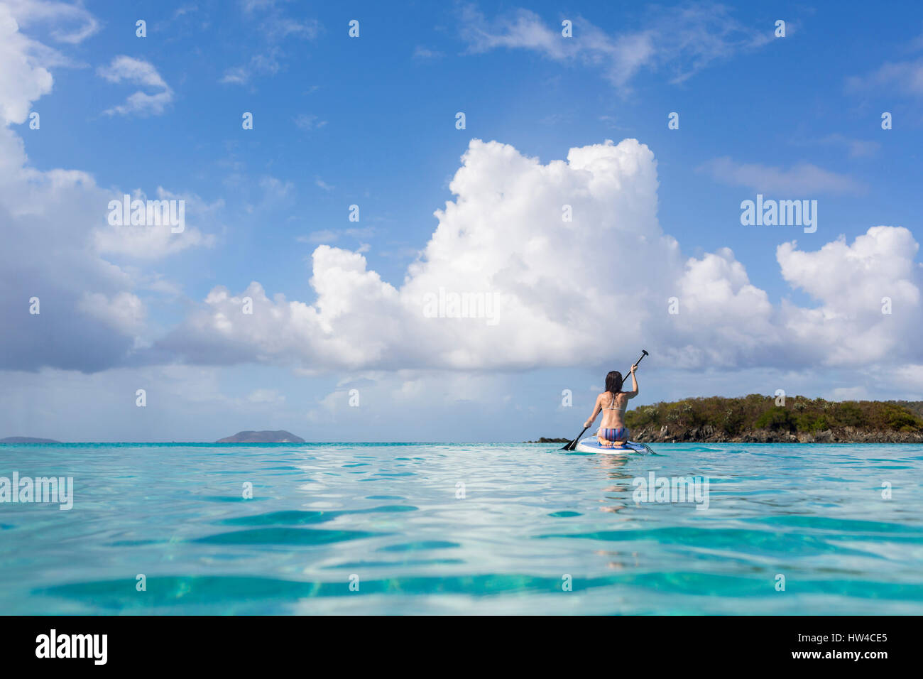 Kaukasische Frau paddeln Surfbrett am tropischen Ozean Stockfoto