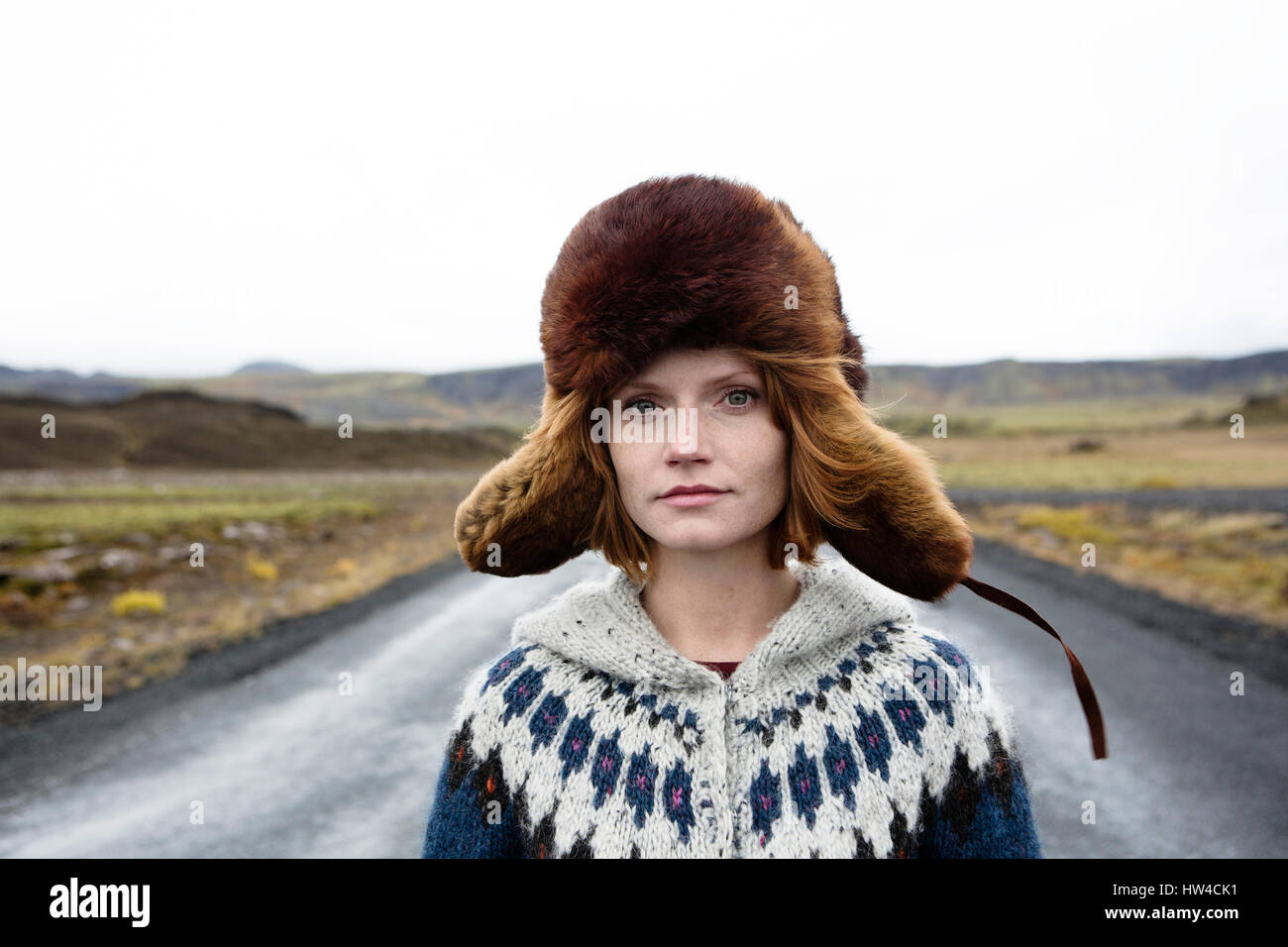 Kaukasische Frau trägt Pullover und Pelzmütze in der Mitte der Straße Stockfoto