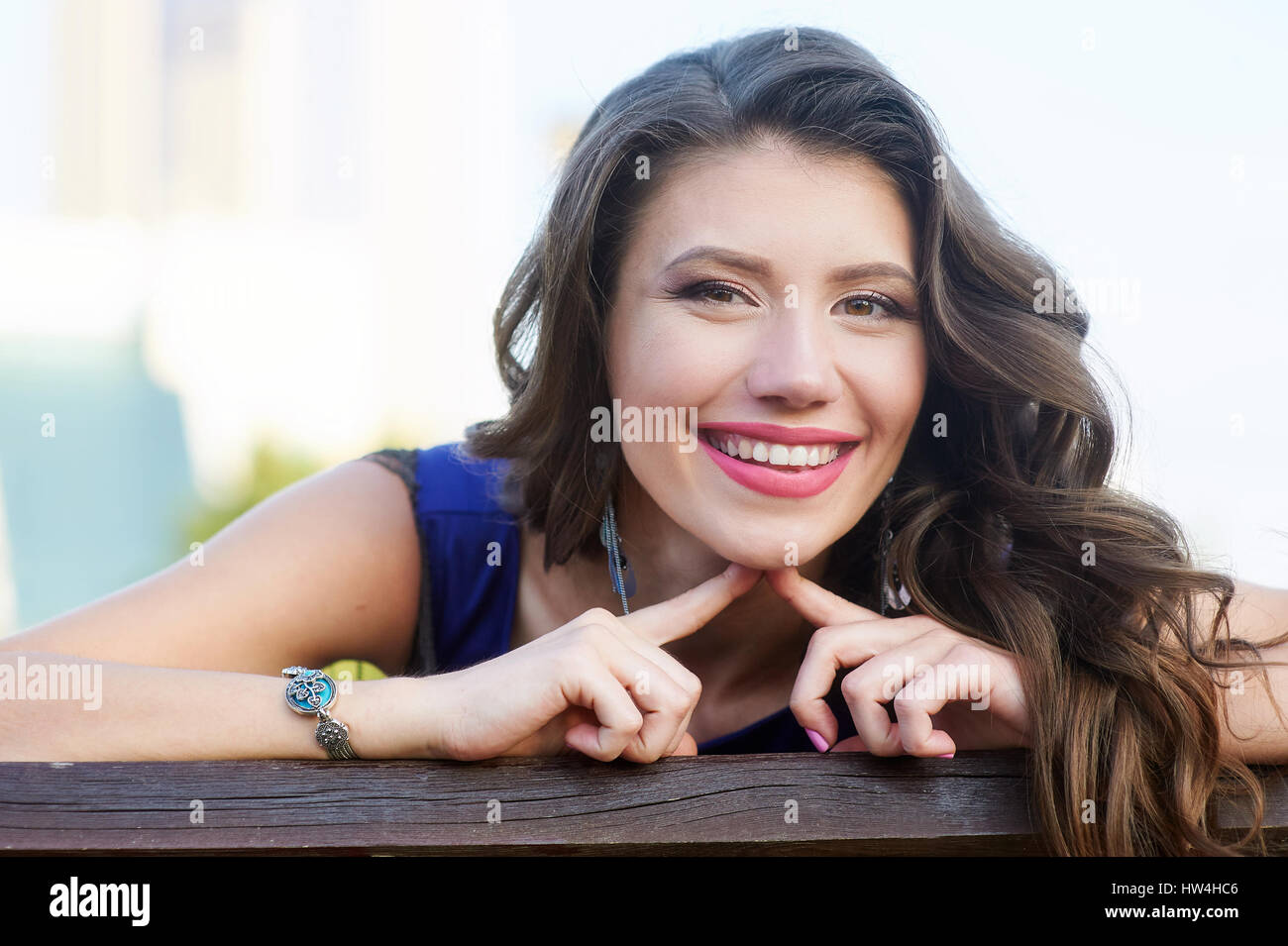 Schöne Brünette Frau sitzt auf der Bank im park Stockfoto