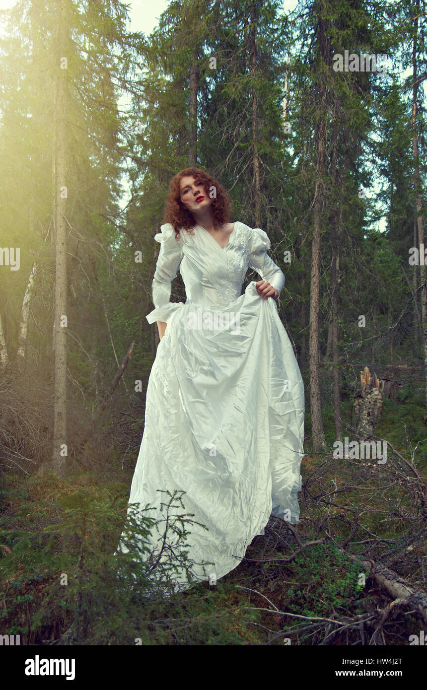 Junge Frau im weißen langen Kleid in den mystischen Wald. Stockfoto