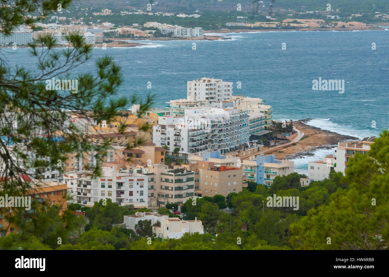 Blick von den Hügeln in St. Antoni de Portmany & Umgebung auf Ibiza.  Hotels am Strand entlang, Unterkünfte.  Wellen als Brandung ans Ufer. Stockfoto