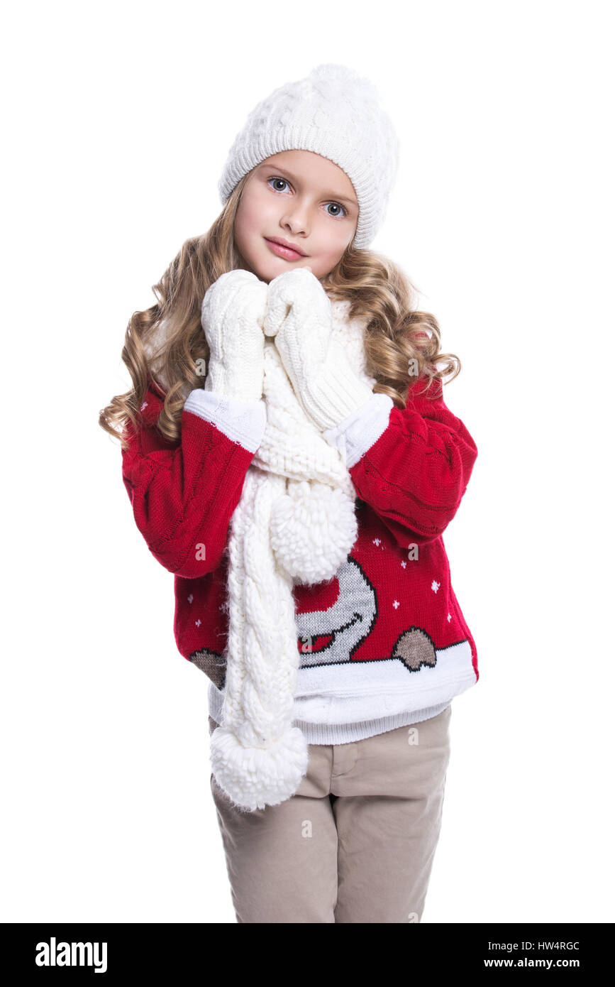 Niedliche kleine lächelnde Mädchen mit lockige Frisur tragen, gestrickte Pullover, Schal, Mütze und Handschuhe isoliert auf weißem Hintergrund. Winterkleidung Stockfoto