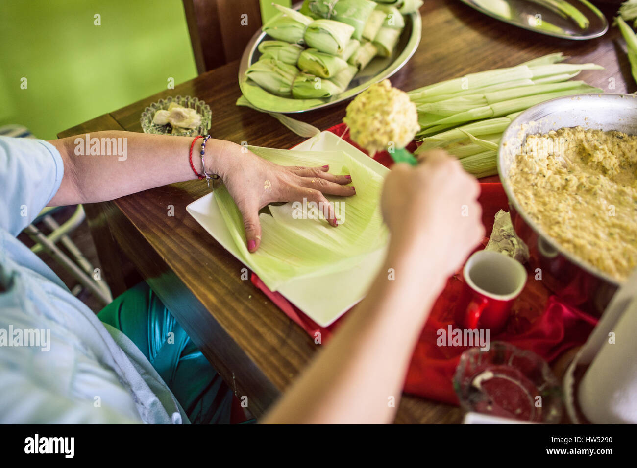 Eine Frau, die eine mittelamerikanische Gericht namens "Tamales". Es ist ein Gericht aus Masa die steckt in Mais Schale und gedünstet werden. Stockfoto