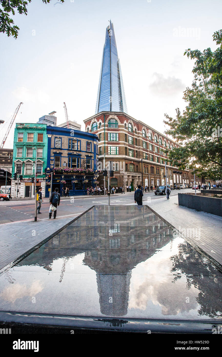 Fußgänger gehen auf einer Straße in London, Vereinigtes Königreich. Hinter den Häusern ist das höchste Gebäude in der Europäischen Union namens "The Shard" risi Stockfoto