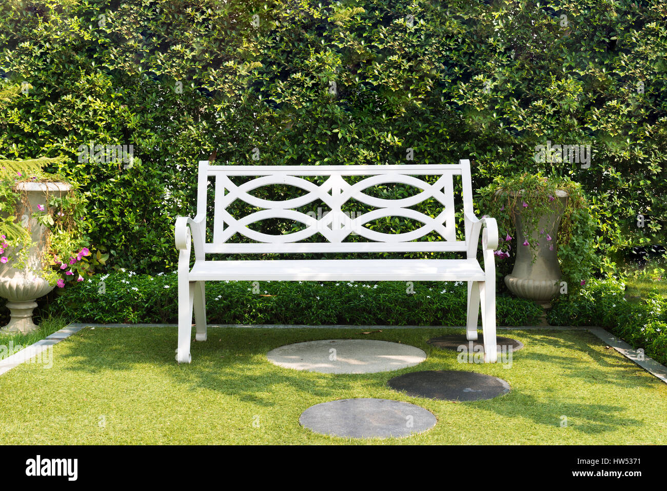 Weiße Holzbank Stuhl mit Bush Hintergrund im Garten zu Hause. Stockfoto