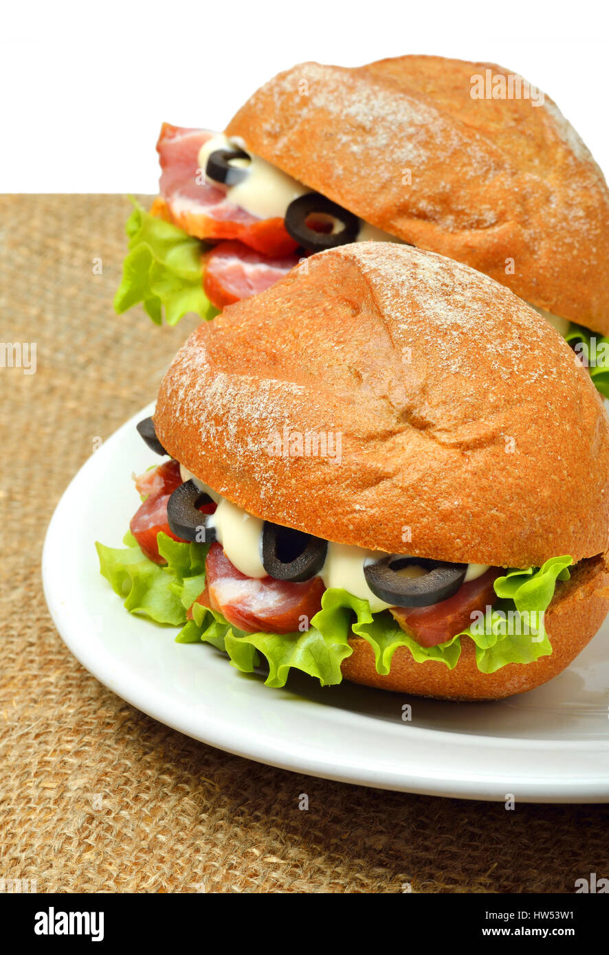 Leckere frische Sandwiches mit grünem Salat, Schinken und Oliven auf weißen Teller auf Entlassung isoliert auf weißem Hintergrund Stockfoto