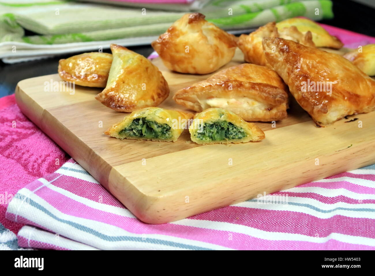 Lachs und Spinat gebackenen Blätterteig Taschen auf einem Holzbrett liegend lila Küchentücher - frisch gebackenen goldenen Farbe Stockfoto