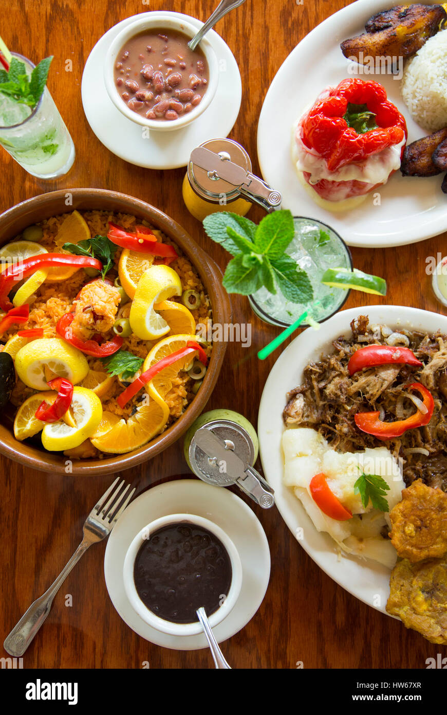 Spanische Gerichte mit Paella, Schweinefleisch, Bohnen, Reis, Paprika, Tostones und mojitos Stockfoto